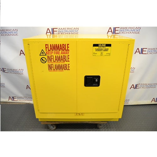 Front perspective view of yellow 22-gallon Uline flammable material storage cabinet showing double doors with warning labels and flush handle