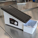 A black paraffin wax trimmer with a grooved surface and a catch basin below.
