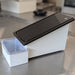 A black paraffin wax trimmer with a grooved surface and a catch basin below.