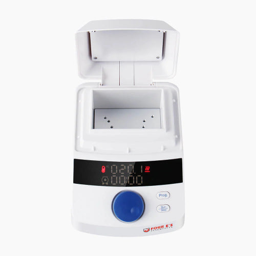Studio front product view of a 4E's USA mini block heater with an open flip-top heated lid against a white background, highlighting its white compact housing, central block chamber, digital LED control panel with a blue rotary knob, and function buttons