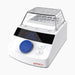 Studio low-angle product view of a 4E's USA mini block heater with a clear removable non-heated lid and a loaded sample block against a white background, highlighting its white housing, Four E's branding, digital LED panel, and blue control dial