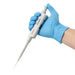 Studio product view of a 4E's USA Precipette adjustable pipette (5-50uL) held at an angle in a gloved hand against a white background, highlighting its ergonomic white body, light green plunger cap, and attached yellow pipette tip