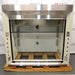Front eye-level view of a 5-foot Jamestown bench fume hood mounted on a wooden pallet, featuring an open sash workspace, a stainless steel header and deck, and side utility panels with electrical outlets