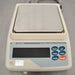 Straight-on elevated studio view of an A&D GF-4000 precision balance on a metallic surface, displaying the square stainless steel weighing pan, beige housing, digital vacuum fluorescent display, and operational keypad