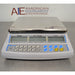 Straight-on studio view of an Adam Equipment CBC 71a digital counting scale on a metallic surface, showcasing its stainless steel weighing pan, front control panel with numeric keypad, and triple LCD displays for weight, unit weight, and count