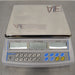 High-angle studio view of an Adam Equipment CBC 71a digital counting scale resting on a metallic surface, showcasing the large stainless steel weighing platter, light grey base housing, and front control console with numeric keypad and triple LCD screens