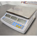 Three-quarter right-angled studio view of an Adam Equipment CBC 71a digital counting scale resting on a metallic surface, featuring the stainless steel weighing platter, light grey base housing, and front control console with numeric keypad and triple LCD screens