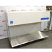An alternative angle view of the Labconco Purifier Horizontal Clean Bench model 3873021, featuring the overhead white housing, expansive stainless steel work surface, and transparent side panels, positioned in front of an American Instrument Exchange backdrop.