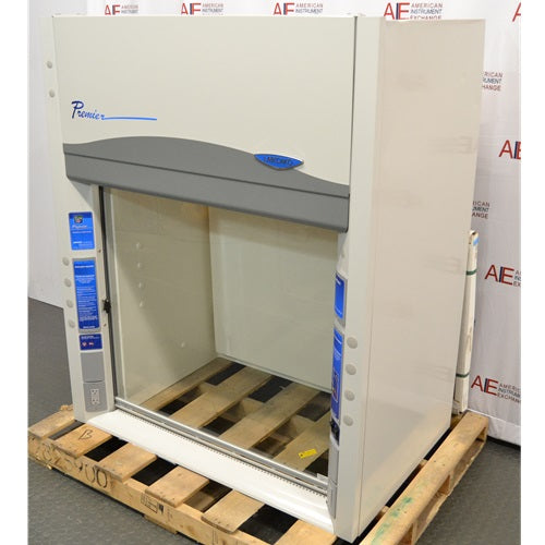 An alternative angled view of a Labconco Protector Premier chemical fume hood mounted on a wooden pallet in front of an American Instrument Exchange backdrop, displaying the right side panel, Premier branding, clear sash, and interior workspace.