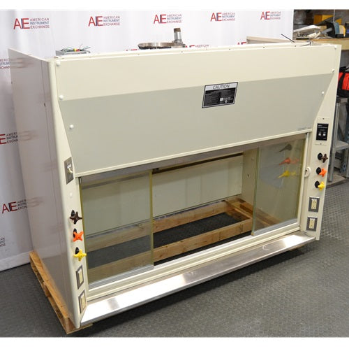 An angled view of the cream-colored Kewaunee 6-foot chemical fume hood, highlighting its sliding glass sash, utility controls, and metal structure against an American Instrument Exchange backdrop.