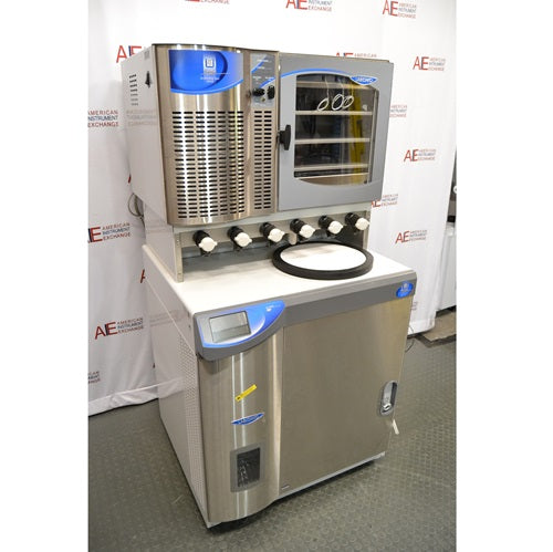 An angled view of the Labconco FreeZone 6-liter freeze dryer system and its attached stoppering tray dryer, showcasing the stainless steel construction, drying ports, and control interface, all positioned in front of an American Instrument Exchange backdrop.