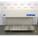 An angled view of the Labconco Purifier Horizontal Clean Bench model 3873021, showcasing the white overhead unit, stainless steel work area, and transparent side panels, positioned in front of an American Instrument Exchange backdrop.