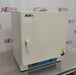 An angled view of a Lindberg Blue M GO1305A laboratory oven sitting on a stainless steel surface in front of an American Instrument Exchange backdrop, displaying its closed door, handle latch, left side panel, and bottom control panel.