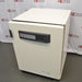 An angled front-right view of a Thermo Heracell VIOS 250i LK CO2 incubator sitting on the floor in front of an American Instrument Exchange backdrop, displaying its closed white front door, dark gray control panel with touchscreen interface, door latch, and right side casing.