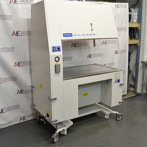 A Baker AniGARD e3 Animal Transfer Station, white in color, with a clear glass window and electronic controls on the top. It is set against a backdrop featuring the AIE Laboratory Services branding.