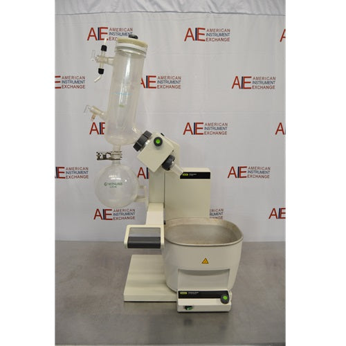 A full front view of a Buchi R-300 rotary evaporator system resting on a metal lab bench against an American Instrument Exchange backdrop, showing the heating bath, lift column, drive unit assembly, glass condenser, and receiving flask.
