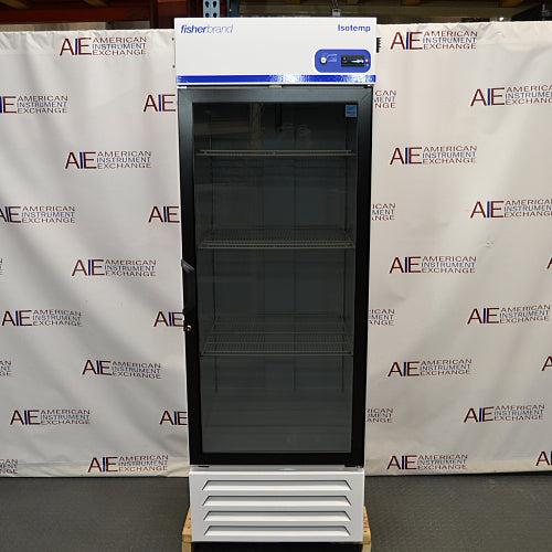 Straight-on studio view of a Fisherbrand Isotemp FBG25RPGA upright laboratory refrigerator standing on a wooden pallet against a branded backdrop, featuring a full-length black-framed glass door, top-mounted digital display console, and louvered white base