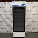 Straight-on studio view of a Fisherbrand Isotemp FBG25RPGA upright laboratory refrigerator standing on a wooden pallet against a branded backdrop, featuring a full-length black-framed glass door, top-mounted digital display console, and louvered white base