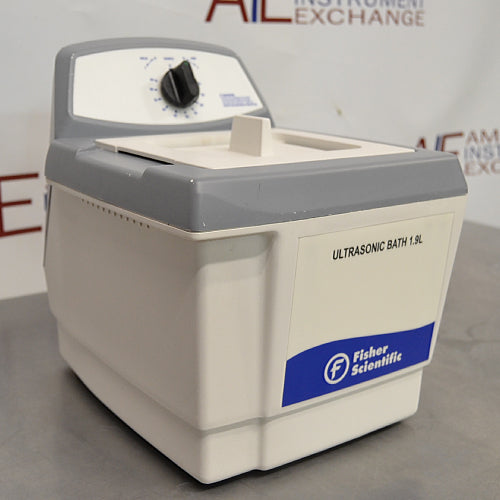Three-quarter side-angled studio view of a Fisher Scientific M1800 1.9L ultrasonic bath on a stainless steel surface, featuring its white and grey housing, front branding panel, and rear mechanical timer dial