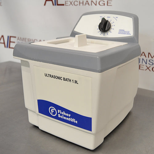 Three-quarter right-angled studio view of a Fisher Scientific M1800 1.9L ultrasonic bath on a stainless steel surface, featuring its white and grey composite housing, covered tank, and rear control console with a timer dial