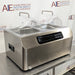 Front-angled view of Four E's USA 24L Per4mance stainless steel water bath featuring dual transparent gable covers, a digital control panel, side carrying handles, and an American Instrument Exchange backdrop