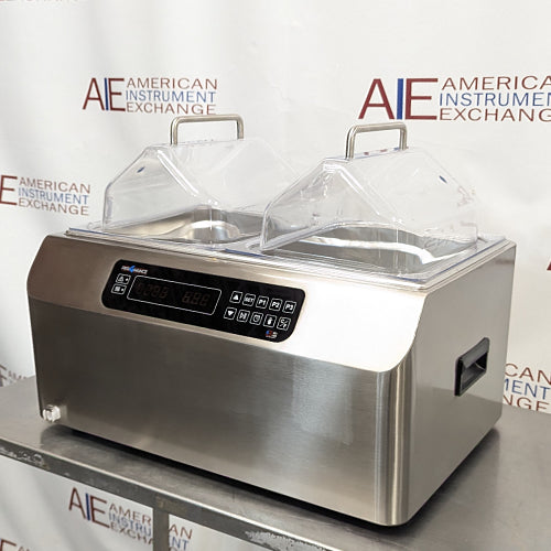 Front-right angled view of Four E's USA 24L Per4mance stainless steel water bath featuring dual transparent gable covers, digital control panel, and side carrying handle against an American Instrument Exchange backdrop