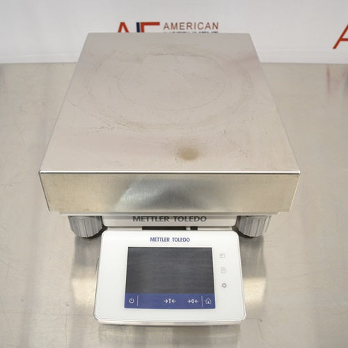 A front-facing overhead view of a Mettler Toledo XSR32001DR laboratory balance available from American Instrument Exchange, showing its large weighing pan and front-mounted digital touchscreen display.
