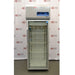 A front-facing view of a Thermo Scientific TSX1205GA laboratory refrigerator available from American Instrument Exchange, showing its glass door, internal wire shelving, and top-mounted digital control panel.