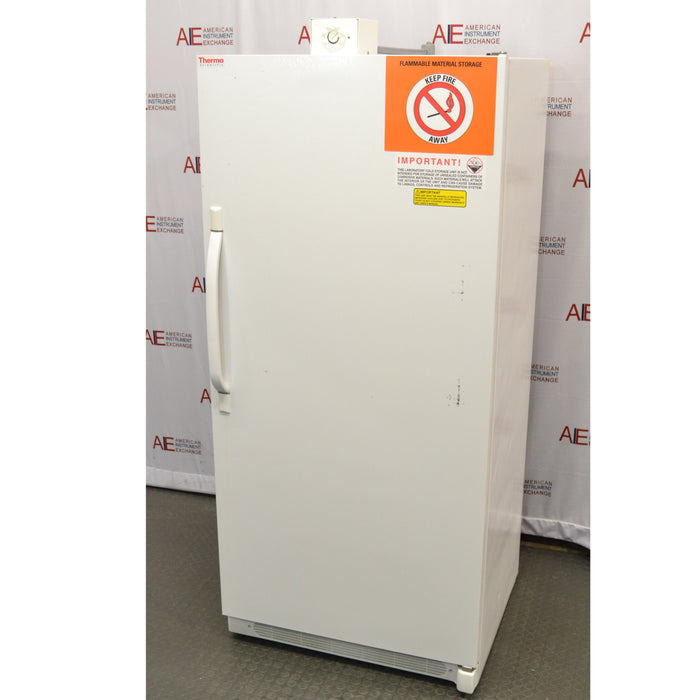 A front-right angled view of a white Thermo Scientific 3552-10A flammable material storage freezer standing on a lab floor, showing the main door panel, vertical handle on the left, top control unit, and orange safety warning decal on the top right against an American Instrument Exchange backdrop.