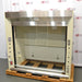 A front angle view of a Jamestown chemical fume hood mounted on a wooden pallet in front of an American Instrument Exchange backdrop, displaying its stainless steel upper header, clear glass sash, and side utility controls.