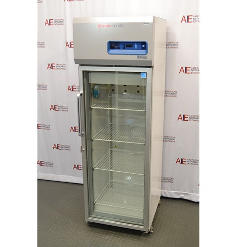 A front-facing view of a Thermo Scientific TSX1205GA laboratory refrigerator available from American Instrument Exchange, showing its glass door, internal wire shelving, and top-mounted digital control panel.