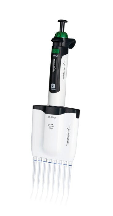 A front view of an upright BRANDTECH Transferpette pro-8 channel adjustable pipette featuring a white body with green accents, a digital volume display window, top plunger button, and eight clear pipette tips attached at the base - American Instruments