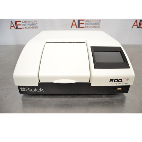 A front view of a white and black BioTek 800 TS absorbance microplate reader featuring a top-loading microplate door, a touchscreen control panel, and a USB port on the lower front panel against an American Instrument Exchange backdrop.