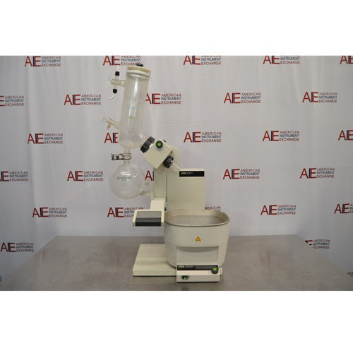 A full front view of a Buchi R-300 rotary evaporator system sitting on a metal laboratory table in front of an American Instrument Exchange backdrop, featuring the heating bath, lift column, drive unit, glass condenser assembly, and attached receiving flask.