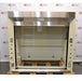 A front-facing view of a Jamestown chemical fume hood in front of an American Instrument Exchange backdrop, featuring a stainless steel header, clear glass sash, internal utility valves, and side electrical outlets.