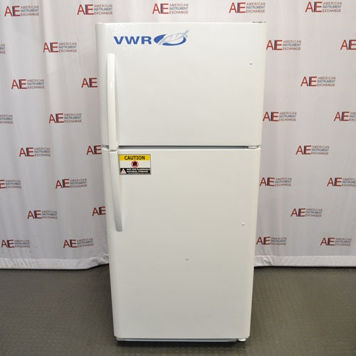 A front-facing view of a white VWR general purpose laboratory refrigerator/freezer combo in front of an American Instrument Exchange backdrop, featuring a top freezer compartment, bottom refrigerator compartment, vertical door handles, and a yellow caution label.