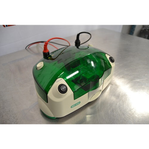 An elevated front-left view of a Bio-Rad MicroRotofor Cell unit resting on a stainless steel surface, highlighting the green tinted lid, attached red and black electrode cables, cooling rocker switch, and side casing.