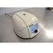 An elevated front-left view of a closed Oxford Lab Products Benchmate C12V microcentrifuge sitting on a stainless steel surface, highlighting the top lid, power cord, and front control panel with illuminated display.