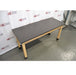 An elevated front-left view of a wooden laboratory bench with a black epoxy resin tabletop supported by four light wood legs with protective black base caps against an American Instrument Exchange backdrop.