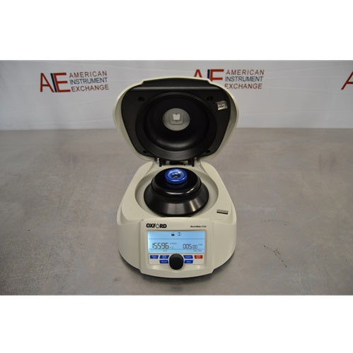 An elevated front view of an open Oxford Lab Products Benchmate C12V microcentrifuge showing the open upper lid, internal rotor assembly with a blue center cap, and digital display panel against an American Instrument Exchange backdrop.
