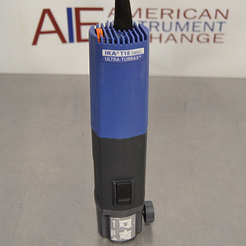 Straight-on studio view of the blue and black IKA T18 basic Ultra-Turrax homogenizer drive motor unit standing upright on a metallic surface, showing its cooling fins, front label, and lower mounting collar
