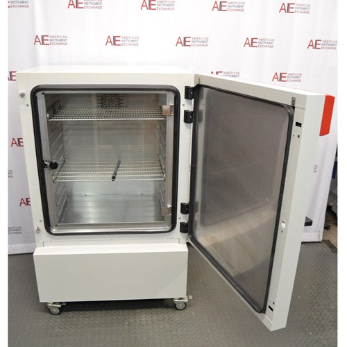 The interior of an open Binder KB240 refrigerated incubator showing adjustable wire shelving and the door seal, set against an American Instrument Exchange backdrop.
