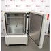 The interior of an open Binder KB240 refrigerated incubator showing adjustable wire shelving and the door seal, set against an American Instrument Exchange backdrop.