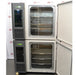 The interior view of a stacked Caron 6010-1 environmental chamber system with the outer doors open, revealing the stainless steel shelving inside each chamber, positioned in front of an American Instrument Exchange backdrop.