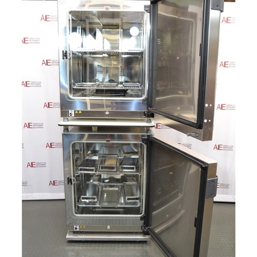 An interior view of two stacked, open-door Thermo Scientific Heracell VIOS 250i CR CO2 incubators available from American Instrument Exchange, showing the internal shelving and stainless steel construction.