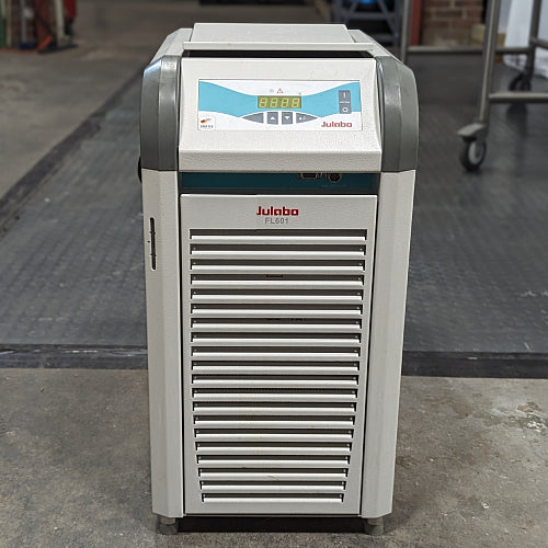 A Julabo FL601 recirculating chiller, with a gray body and blue details, standing on a warehouse floor.
