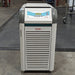 A Julabo FL601 recirculating chiller, with a gray body and blue details, standing on a warehouse floor.