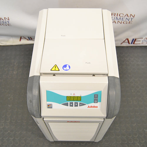 A Julabo FL601 recirculating chiller, with a gray body and blue details, standing on a warehouse floor.