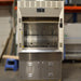 Full-front studio view of a Kewaunee 4-foot laboratory fume hood featuring a beige superstructure with a sliding glass sash, built-in electrical outlets and service fixtures on the side panels, and a stainless steel storage base cabinet with louvered double doors