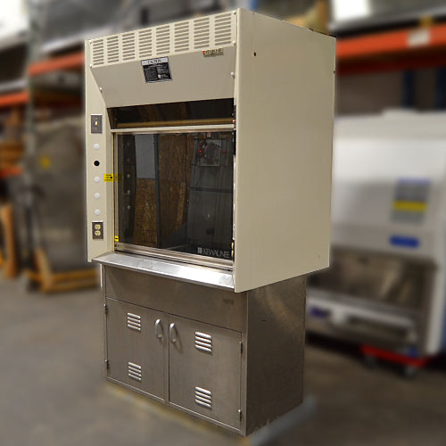 Three-quarter side-angled studio view of a Kewaunee 4-foot laboratory fume hood showing the beige upper enclosure, sliding glass sash, left side pillar with electrical outlets, and the stainless steel storage cabinet base
